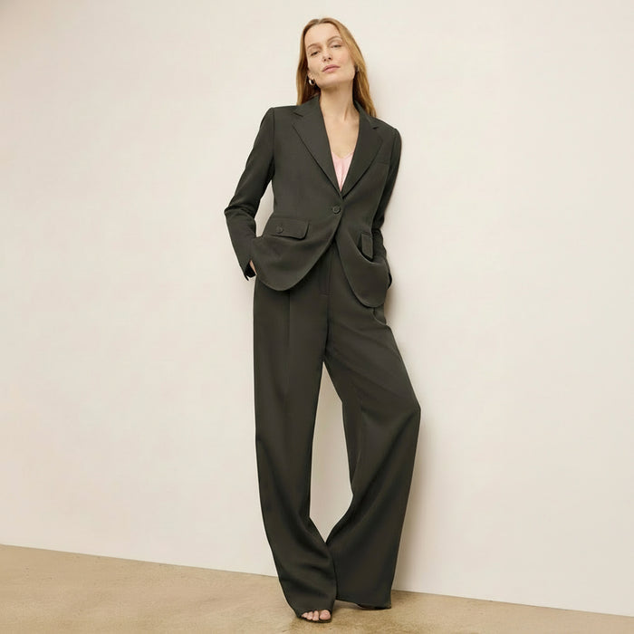 Woman wearing a dark gray suit against a plain background
